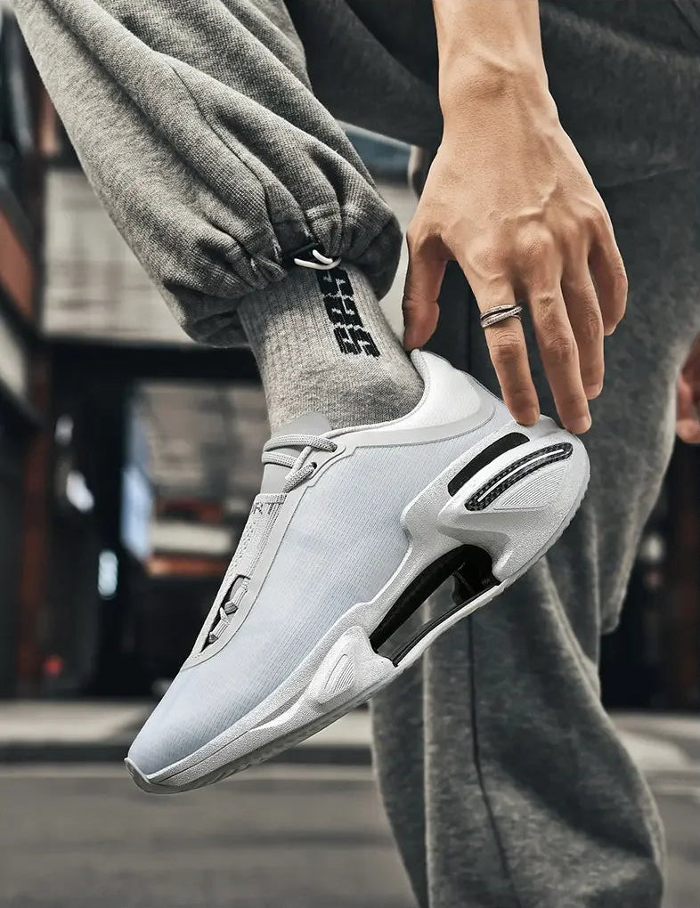 White athletic shoe with black accents worn by a person in gray pants.