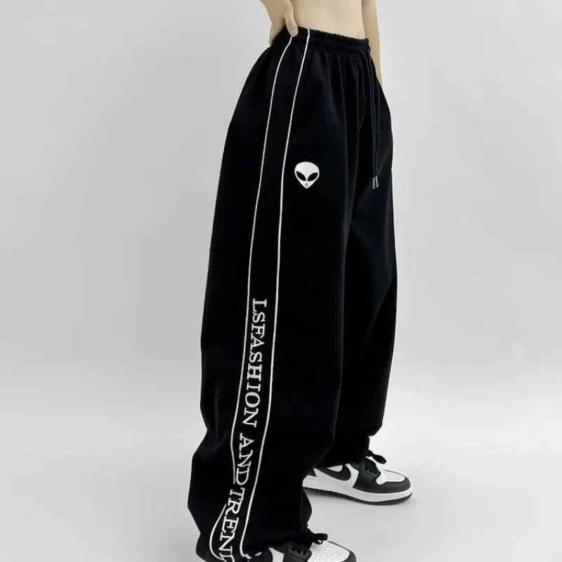 Front view of model wearing black American style printed sweatpants with white lettering